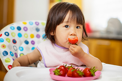 A toddler eating strawberries