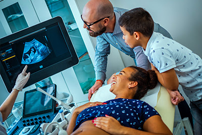A mother having an ultrasound with husband and son