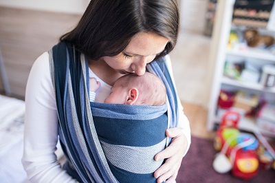 Mother kissing baby asleep in the sling