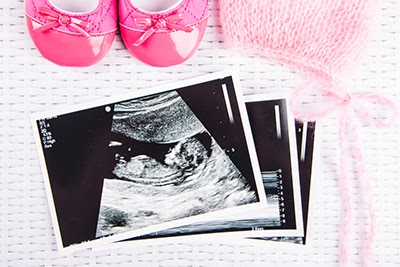 Ultrasound photos and pair of baby girl slippers