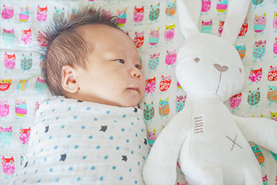 Swaddled baby sleeping with open eyes
