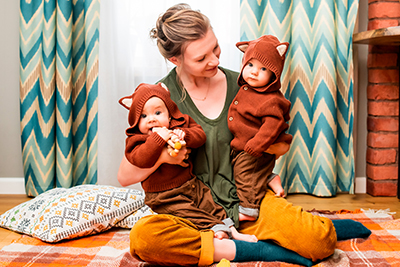 happy young mom playing with twins kids sitting on blanket at home